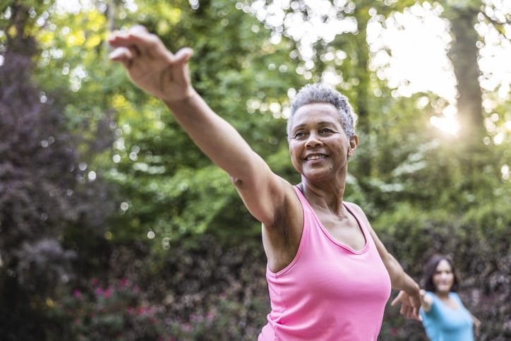 Photo shows a senior woman taking a yoga class outside/Getty Images