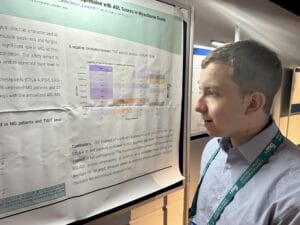 Israeli myasthenia gravis researcher Garrick Hoichman with the poster of a clinical trial conducted by Hadassah University Medical Center in Jerusalem