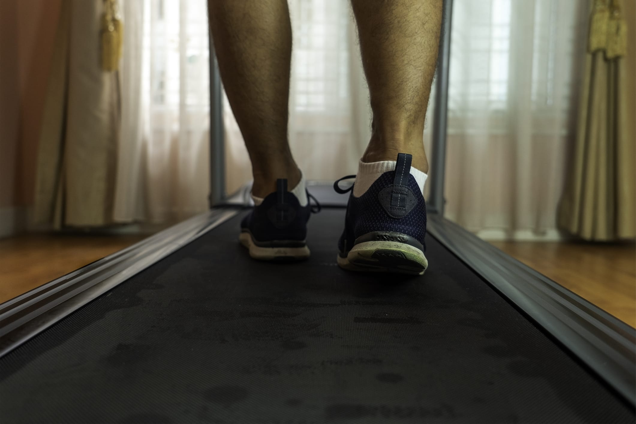Close-up of a man wearing blue sports sneakers walking on a treadmill