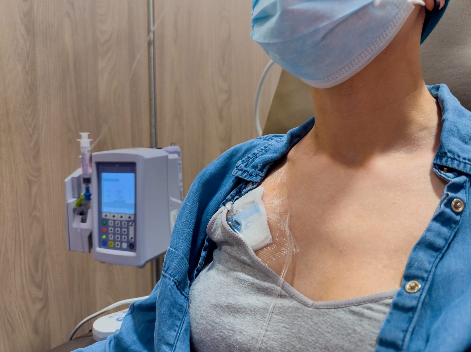Healthcare scene showing a person with a protective mask attached to an IV drip by a digital infusion device