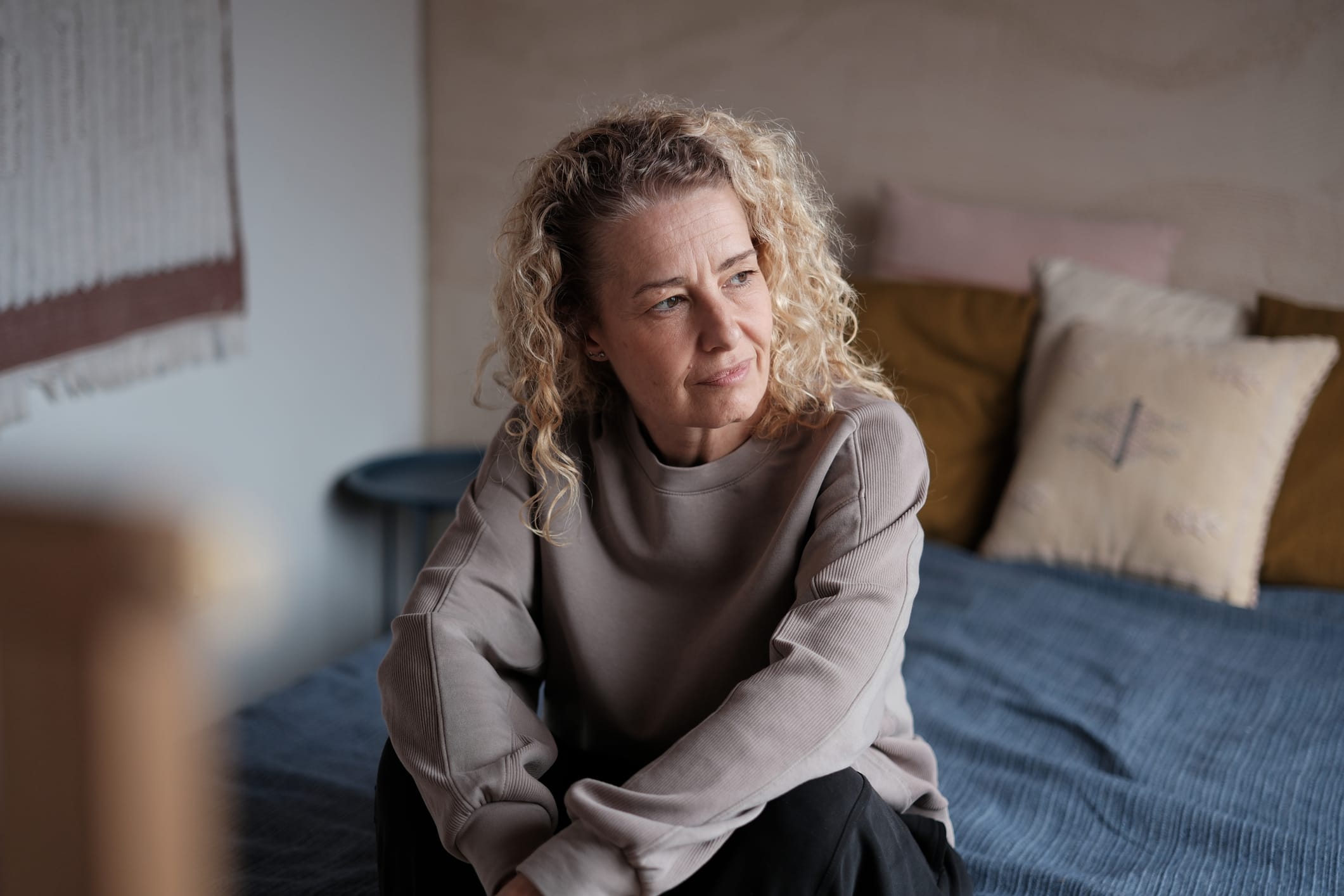 Middle-aged woman sitting on bed looking tired