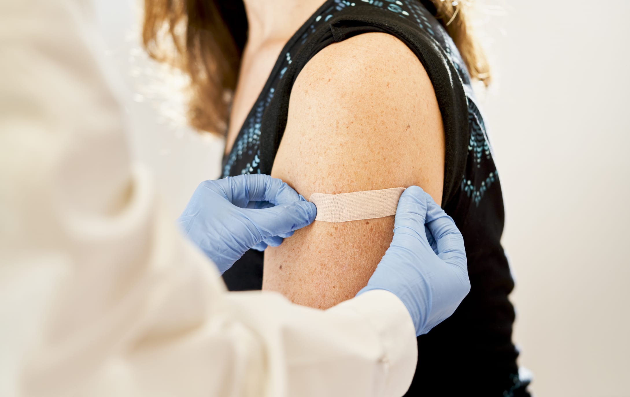 Doctor applying band-aid to his patient after dose of vaccine for immunization