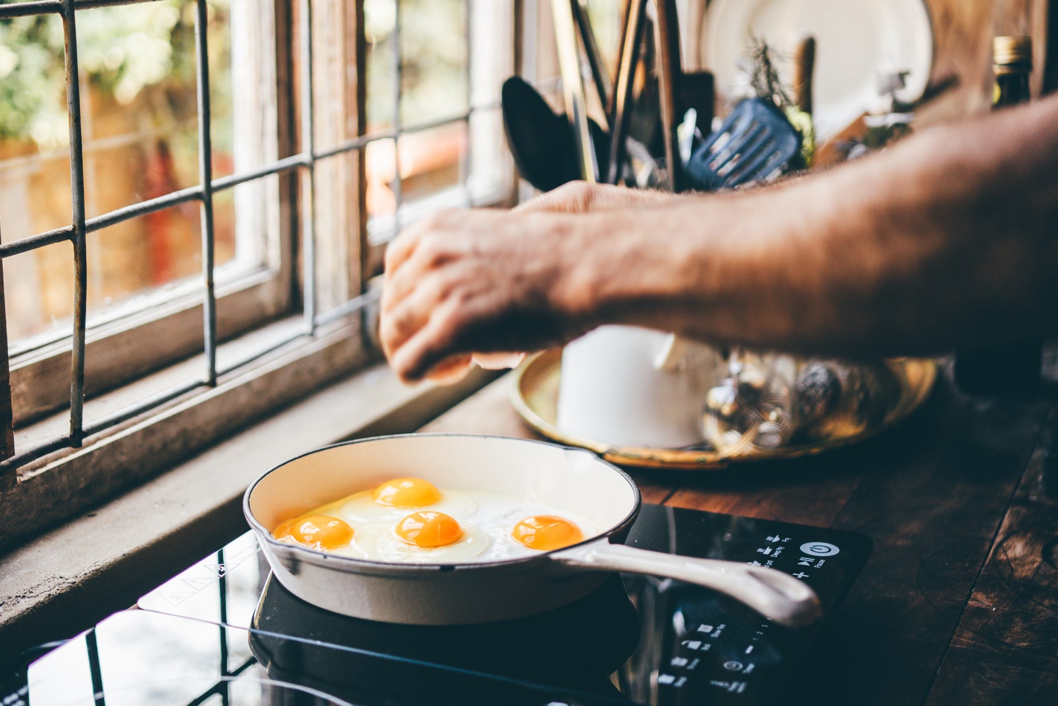 Man cracking eggs in frying pan