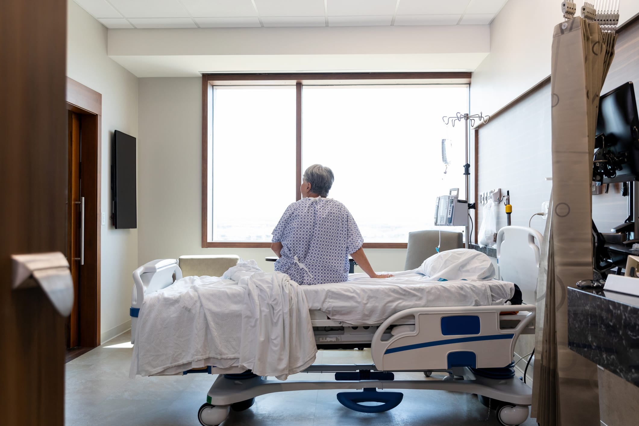 Senior woman in a hospital gown sitting on a hospital bed